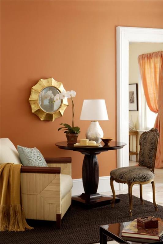 stena marelične barve, baročni stol, stara okrogla miza, majhna rjava preproga