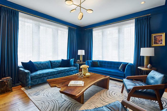 trendovska barva 2020 klasična modra barva, razkošen dekor dnevne sobe z modrimi zofami, modrimi stenami in zavesami, originalno obešeno belo in sivo preprogo