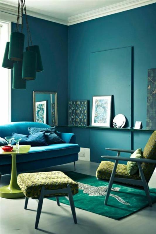stena v barvi race, viseče modre svetilke, modra zofa, zelena miza, okvir vrat