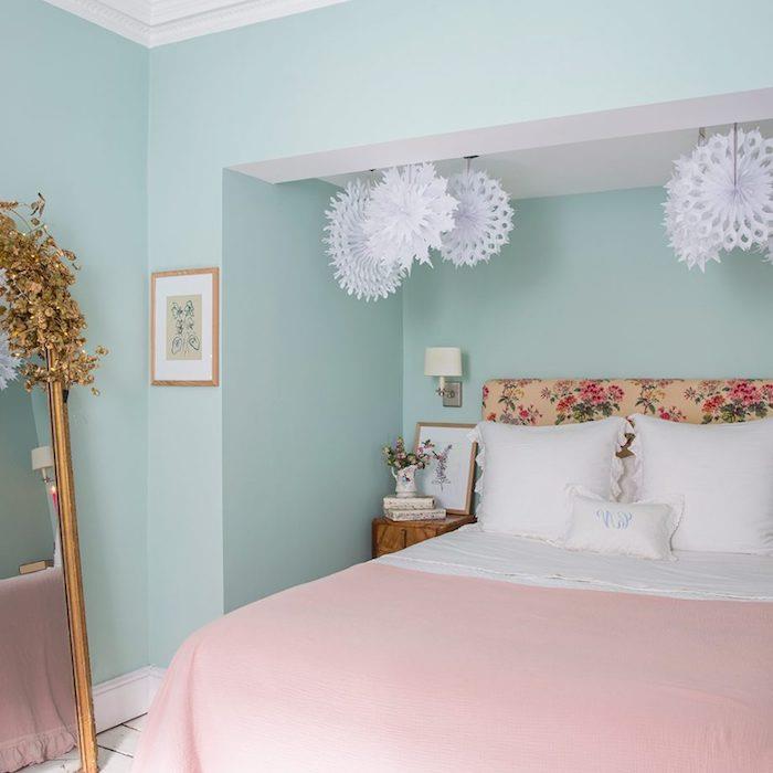 pastelno modra barva spalnice za odrasle in roza posteljnina v prahu, vzglavje s cvetličnim vzorcem, ogledalo v vintage dizajnu, okras iz snežinke iz papirja