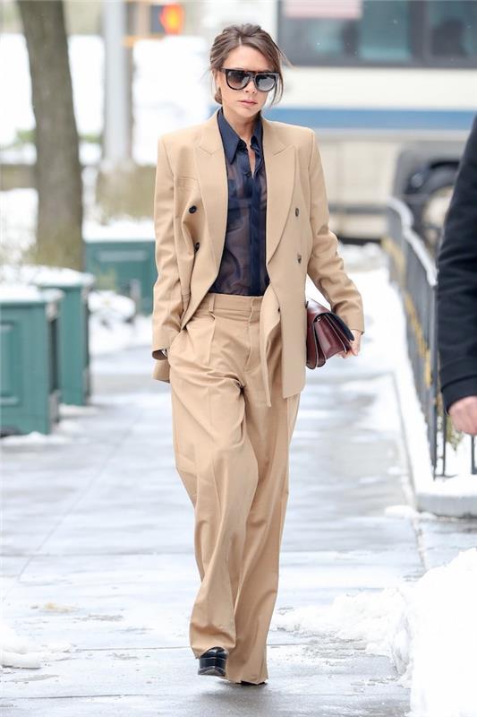 smėlio spalvos kelnės, Victoria Beckham, šukuosena, plaukai surišti į žemą bandelę, juodi odiniai kulniukai