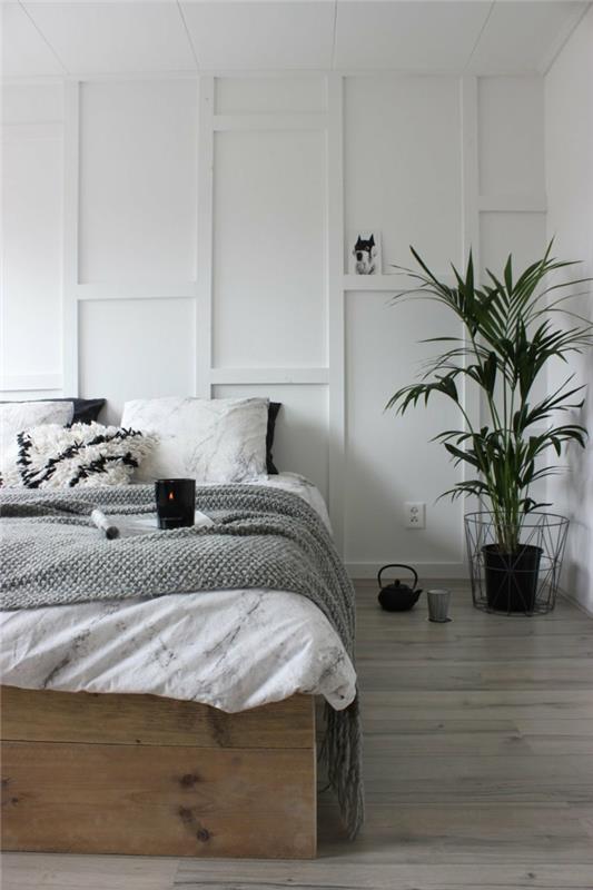 balta miegamojo sienų spalva, didelis puodas su žaliu augalu, juodas arbatinukas ant grindų, minkštos pagalvėlės