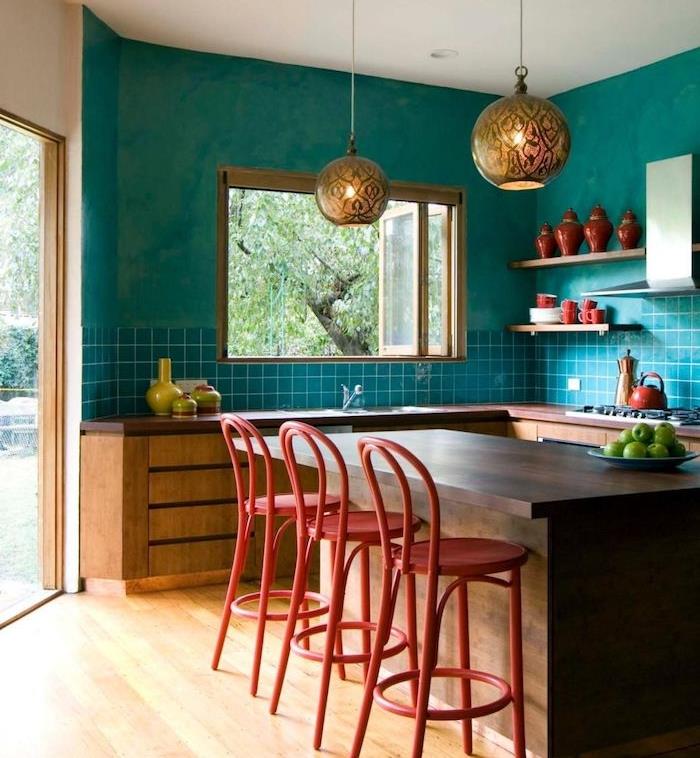 bir mutfağın duvarları için ne renk, turkuaz ve turkuaz fayanslarla yeniden boyanmış model mutfak, merkezi ahşap ada, bar sandalyeleri ve kırmızı dekoratif aksesuarlar
