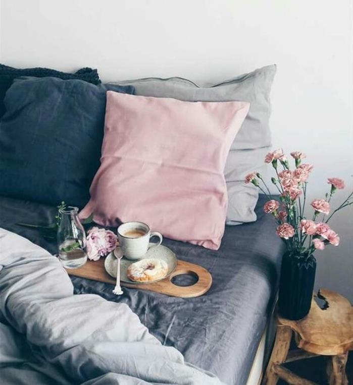 dekor za spalnico, rožnate, sive in modre blazine, bela stenska barva, rože, roza blazina, lesena nočna omarica