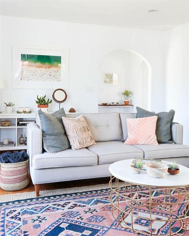 dažų spalvos svetainė, pastelinių spalvų kilimas, perlamutrinė sofa, balta siena, dekoratyvinės pagalvėlės
