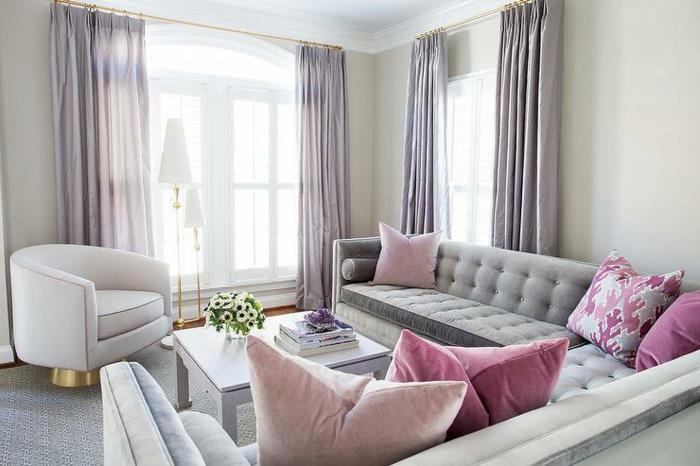 dažų spalvos svetainė, pilka kuokštinė sofa, rožinės pagalvėlės, pilkos užuolaidos, kvadratinis stalas