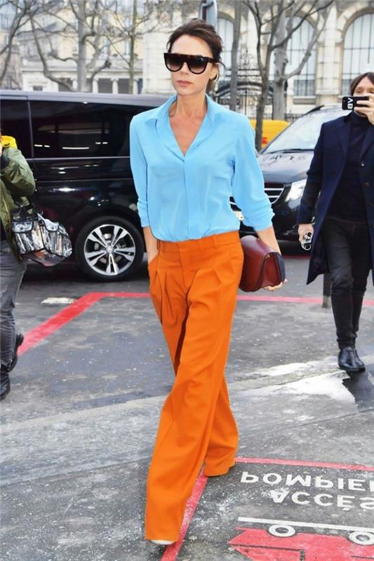 ženski slog oblačenja, oranžni model hlač z žensko srajco v svetlo modri barvi, kombinacija oblačil komplementarnih barv