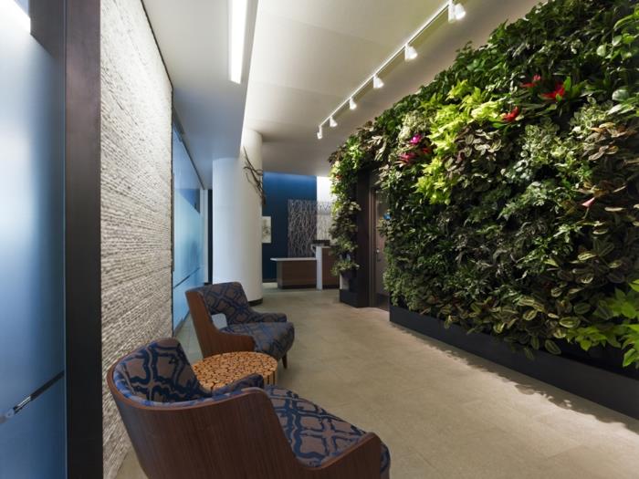 žalia siena koridoriuje, apdaila gyvais augalais, kreminis kilimas, didelės kėdės