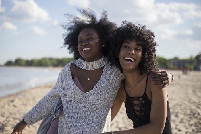 Afriška pletenica model afro frizura pričeske dva prijatelja, ki se nasmehita fotografija na plaži ženska naravni lasje lepa fotografija