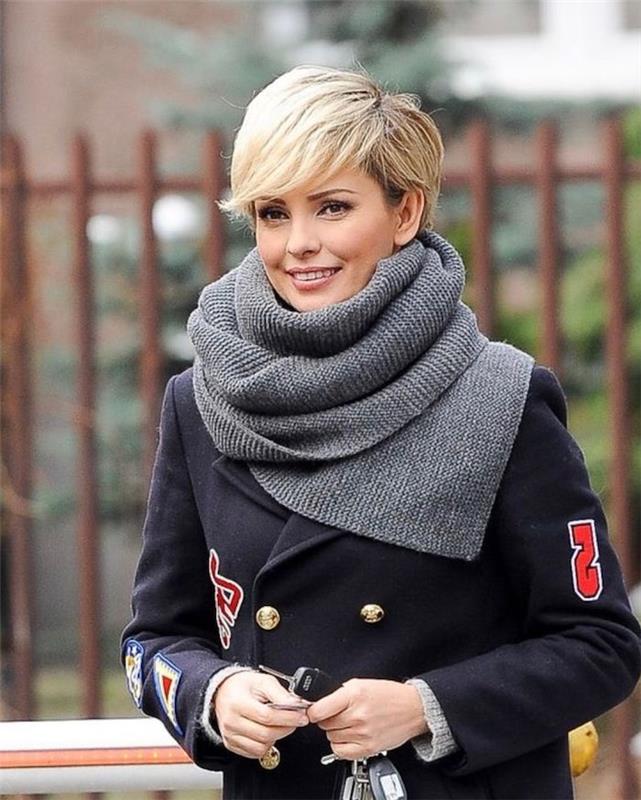 blond kratka frizura z blond koničastimi šiškami v sivi ruti in črnem plašču