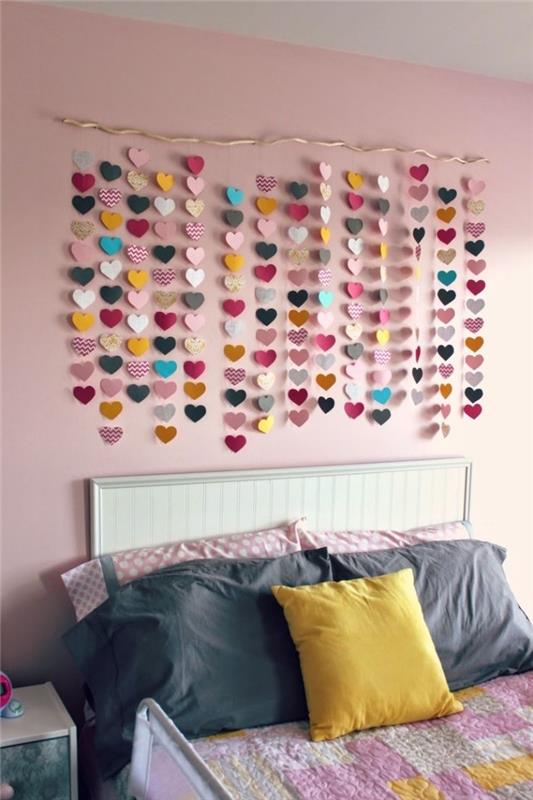 Soluk pembe boyalı duvarda asılı küçük renkli kağıt kalpler ile duvar dekorasyonu