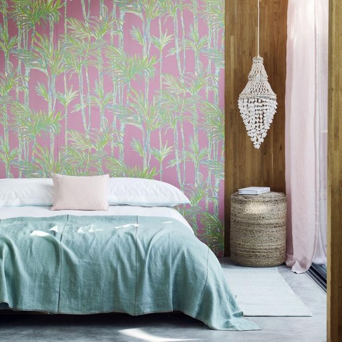 atogrąžų tapetų raštas žalios ir rožinės spalvos baldais apstatytame miegamajame su didele lova ant betoninių grindų