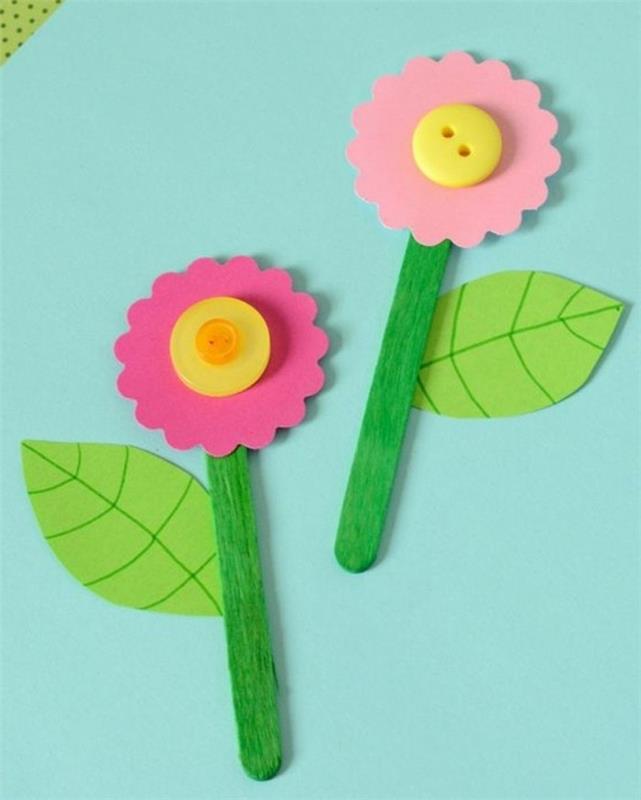 obrtne ideje za otroke, dve rožici iz roza filca, rumeni gumbi in listi zelenega papirja, pritrjeni na sladoledne palčke, pobarvane v zeleno