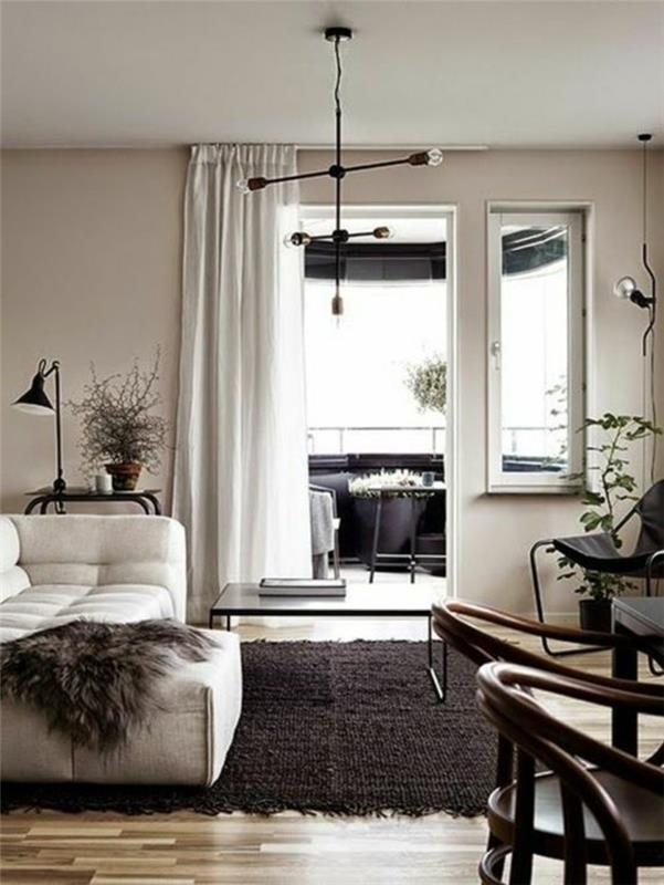 atvira terasa šalia kambario su smėlio ir pilkomis sienomis, beveik balta sofa su tamsiai pilka gyvūnų oda, tamsiai rudas kilimas, svetainės spalvų idėjos