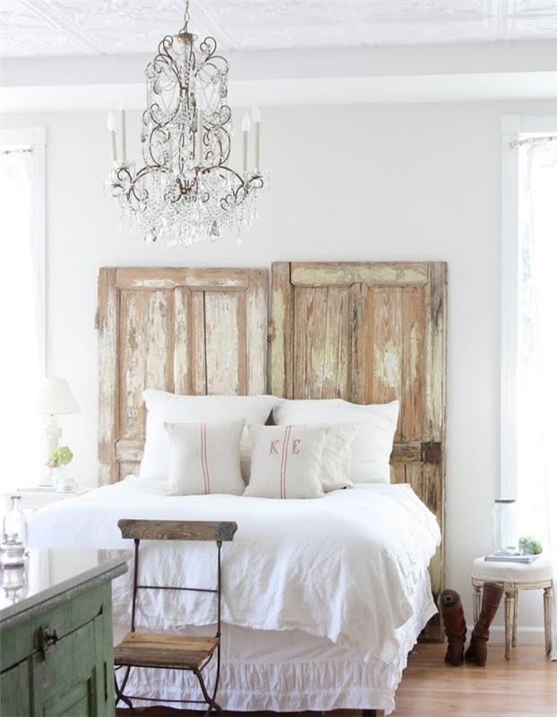ideja za vzglavje s starimi vrati hleva, belo posteljnino, elegantnim baročnim lestencem, lahkim parketom, elegantnim podeželskim pohištvom
