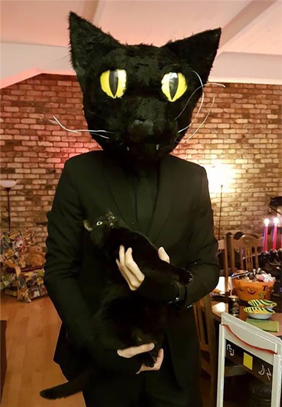 Apsirenkite kaip jo juoda katė, katė su vyru juodame kostiume su juodos katės kauke