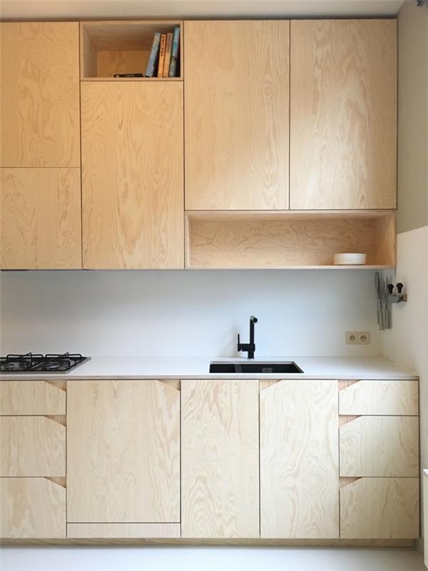 bela in lesena kuhinja z belim pohištvom iz svetlega lesa, belim kuhinjskim modelom in mat črno pipo