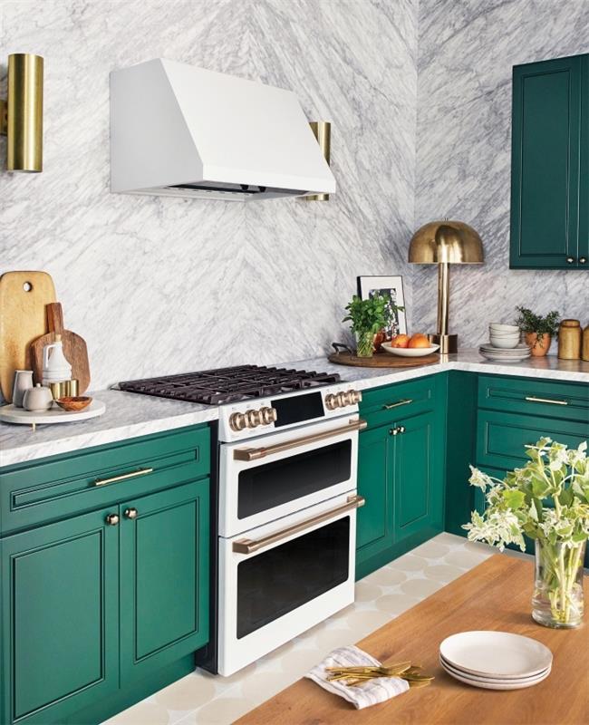 sodoben model kuhinje s stenami iz belega marmorja, opremljene z omarami v zelenih sencah in zlatimi poudarki