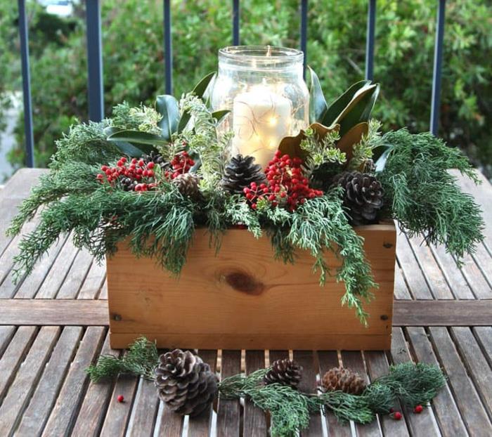 naredite osrednji del z naravnimi predmeti, stekleno posodo z veliko svečo, vejicami in jagodami v leseni škatli