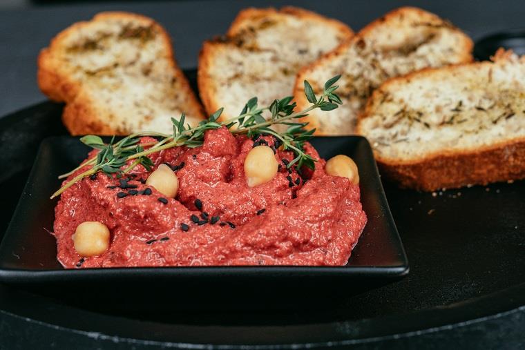 Hummus di cette, bruschette di pane con timo, ciotola con hummus di barbabietole