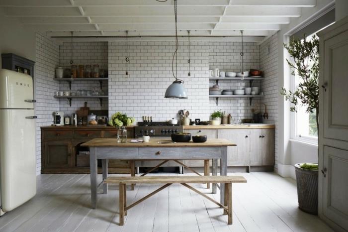 kuhinjski model, velik betonski cvetlični lonček, lesena klop, opečena stena v beli barvi, opremljena kuhinja