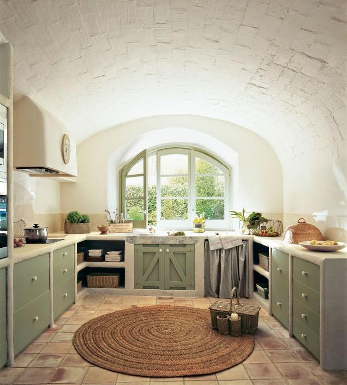 bela in lesena kuhinja, okno s ploščicami v zeleni barvi, kuhinjske omare v kaki zeleni barvi, okrogla preproga, ponev