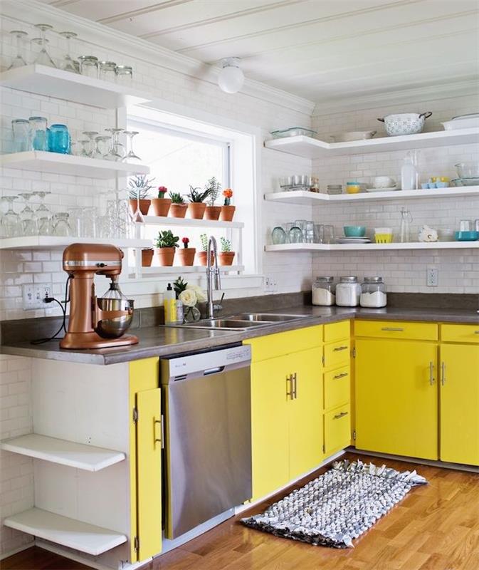 kampinis virtuvės modelis su geltona virtuvės spintele ir antracito pilku stalviršiu, baltos spalvos plytelėmis, baltos lentynos su atidengtais indais, senovinio stiliaus