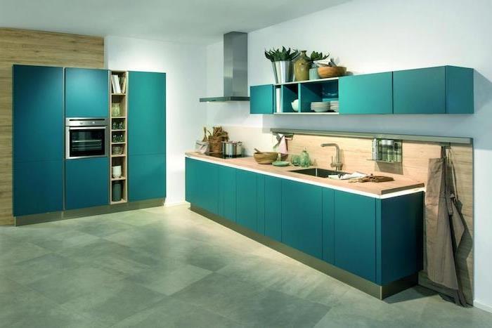 ideje o račji modri kuhinjski opremi na sprednjih straneh kuhinjske omare, tla iz sivih ploščic, lesena delovna plošča in škropljenje, bela stena