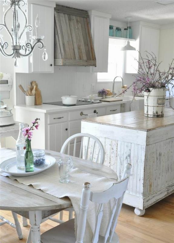 elegantna podeželska kuhinja, kmečka lesena miza, bela kuhinjska sprednja stran, izrabljen lesen osrednji otok, leseni sesalnik, cvetlični okras