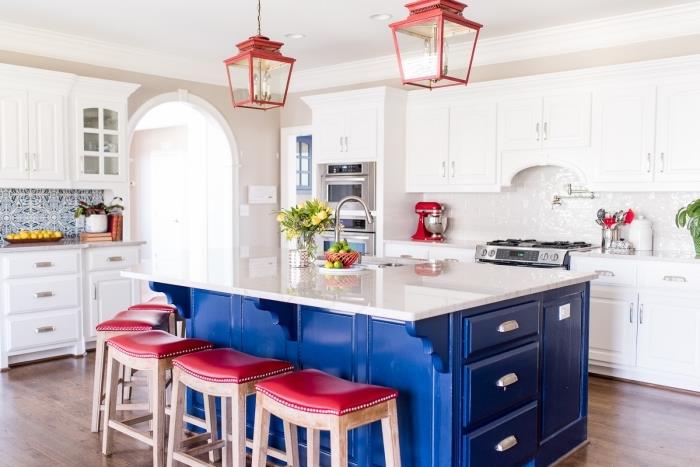 kuhinjske plošče iz cementa, ležalniki in lestenec v rdeči barvi, belo kuhinjsko pohištvo s kovinskimi ročaji