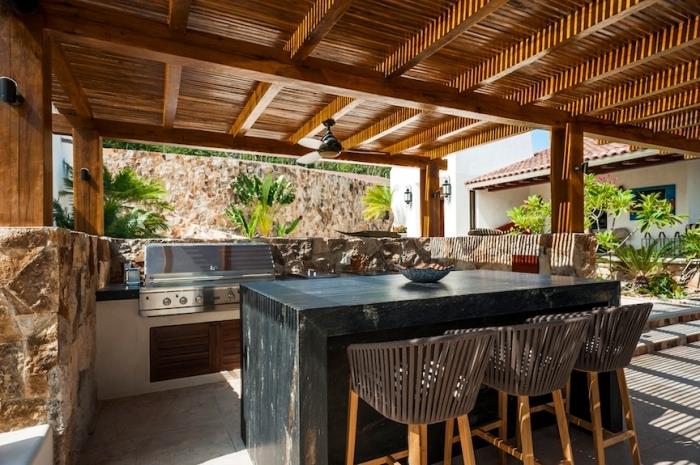 dengtas vasaros virtuvės modelis su mediniu stogu ir lubų ventiliatoriumi, virtuvės išdėstymas su centrine sala iš medžio masyvo