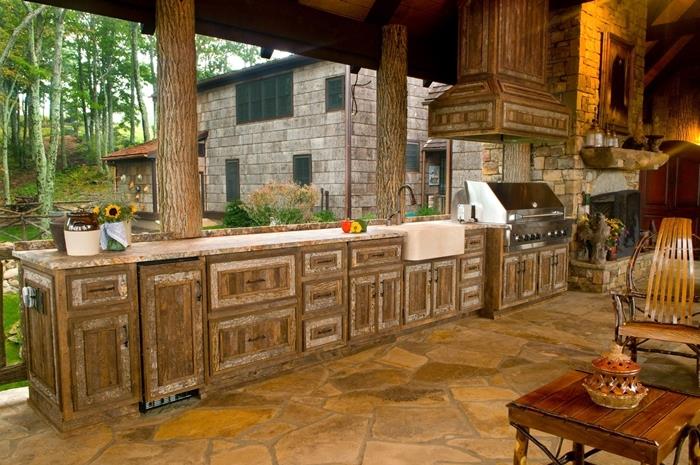 Provansalska poletna kuhinja na prostem, ki dekorira odprte kuhinjske nizke omare iz temnega lesa, omarice iz kamna