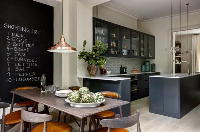 virtuvės sienų skalūnas, ilgas medinis stalas, dviejų spalvų medinės kėdės, prie stiklo montuojamos spintelės, juoda ir balta sala