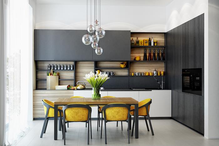 pilka ir balta virtuvė su balta žema spintele, juodomis aukštomis spintelėmis ir mediniu dugnu, originaliais pakabinamais žibintais, mediniu ir metaliniu stalu bei juodos ir geltonos spalvos kėdėmis
