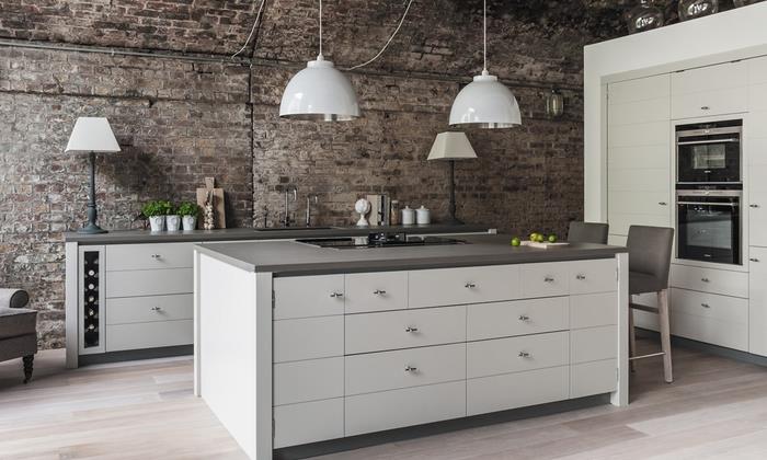 tuğla duvarın ve mat gri mutfak mobilyasının kontrastıyla oynayan modern bir tasarıma sahip endüstriyel bir mutfak