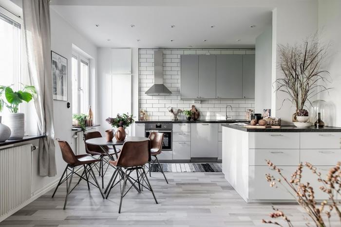 pilkos parketo virtuvės grindys, skandinaviško dizaino kėdės, juodi stalviršiai su baltomis spintelėmis, metro plytelės, skandinaviška virtuvė
