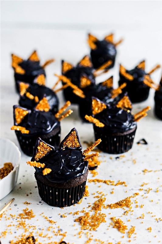 Helovino pyragaičiai su juoda glajumi, dekoruoti auksiniu cukrumi, ir mažas individualus pyragas Helovino proga pasigaminti