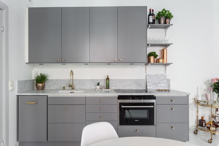 şık ve çağdaş bir görünüm için mat gri mutfak mobilyalarını altın kulplar ve mermer bir tezgahla birleştiren modern ve minimalist gri mutfak