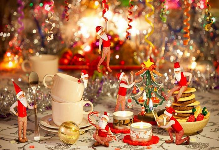 Kalėdų stalo dekoravimas, balti kavos puodeliai, auksinis Kalėdų kamuolys, Kalėdų Senelio žaislai, Kalėdų eglutė, girliandos