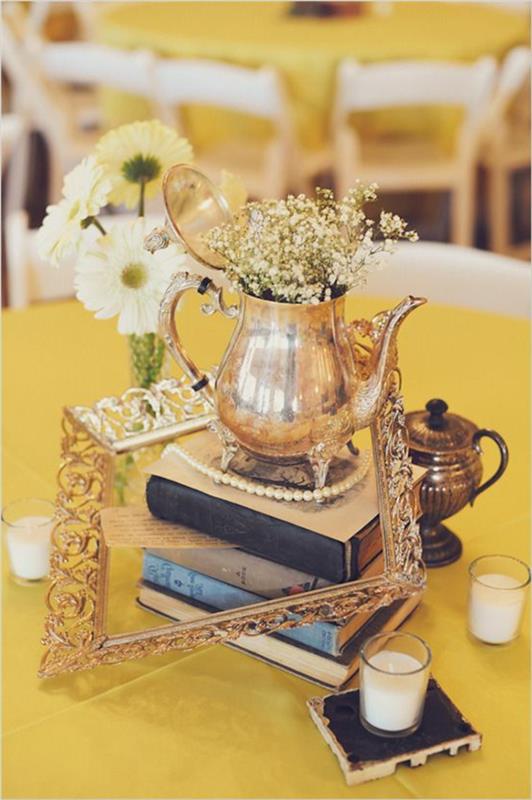 senovinis stalo dekoravimas, senos knygos, auksinis arbatinukas, geltonos staltiesės, baltos kėdės