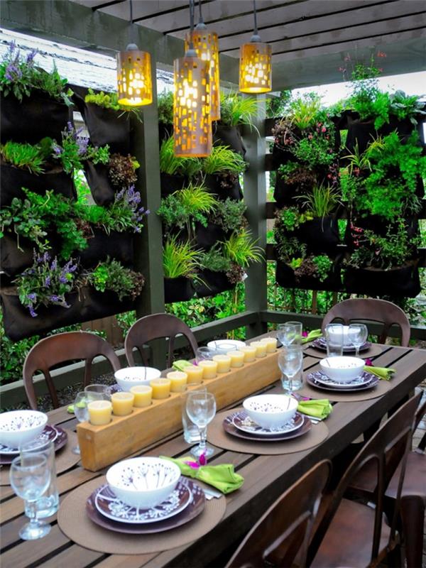 dekoracija dvorišče pergola zunanje pohištvo temni les miza vetrič pogled rastlinska zunanja razsvetljava sveče osrednja miza