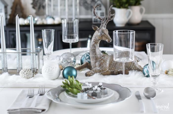 valgomojo dekoras, baltos lėkštės, baltas stalas, vyno taurės, šampano taurės, dekoratyviniai elniai, Kalėdų rutuliai