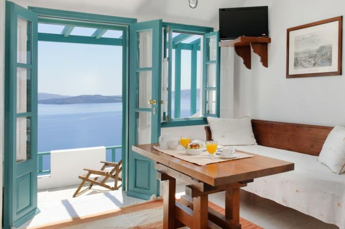 Grški obrok, turkizne rolete, pogled na morje, kavč in lesena miza