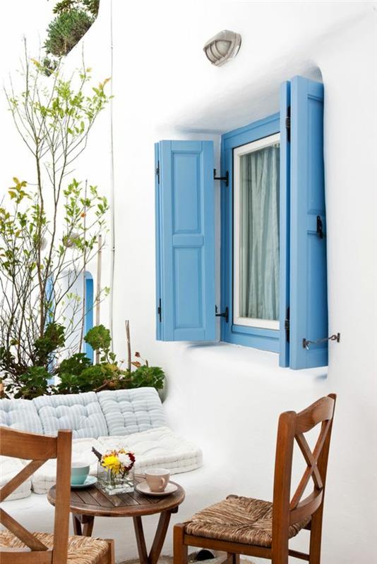 Grško modra na polknih, leseno vrtno pohištvo, zeleno cvetje, bela fasada