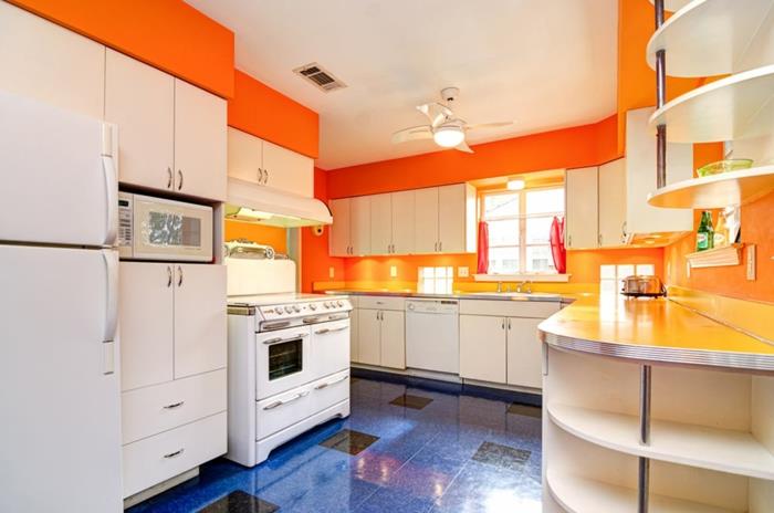 perdažyti virtuvę, liepsnojančios oranžinės spalvos sienas, baltus baldus, karališkos mėlynos ir juodos spalvos plytelių grindis, baltas lubas su ventiliatoriaus šviesa