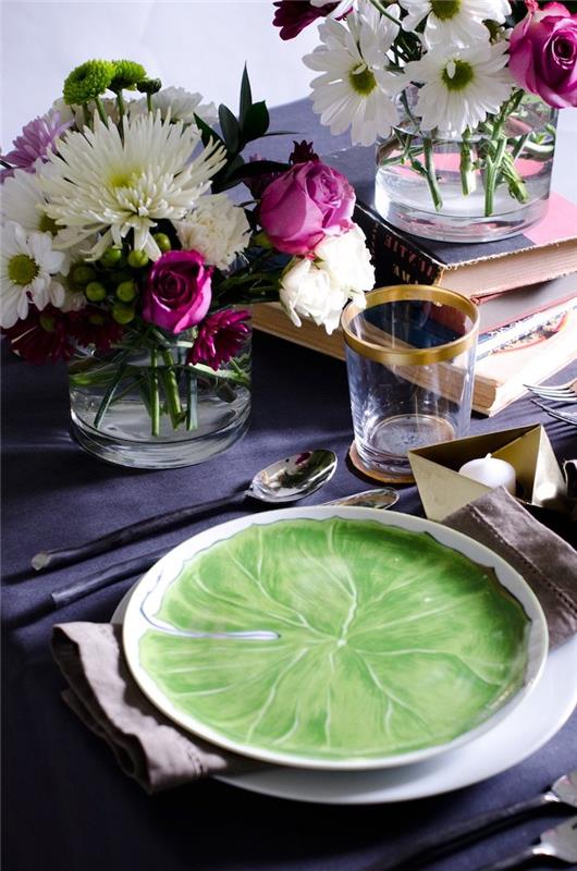meilės puošmena su puokštėmis ant tamsiai mėlynos staltiesės ir žaliai dažytos porceliano lėkštės