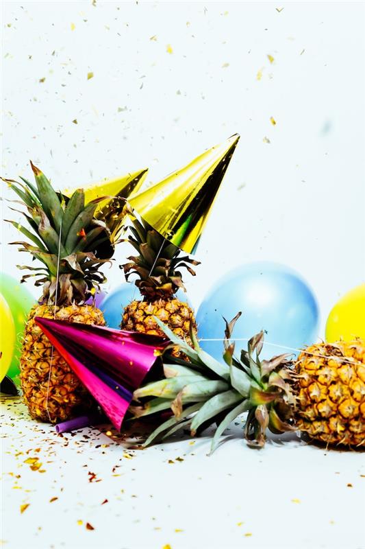ananas decp za novoletni dan z ananasi, pisanimi baloni in klobuki za zabave, obkrožen z dežjem konfetov