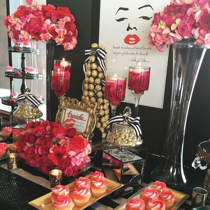marilyn monrie gimtadienio tema su rožinėmis ir raudonomis gėlių puokštėmis, baltais ir raudonais keksiukais, saldainių pyragu ferrero rocher