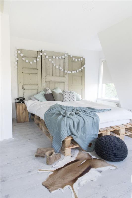 Avrupa palet yatağı ve eski bir kapı başlığı ile geri kazanılan trendi benimseyen hoş bir İskandinav tarzı yatak odası