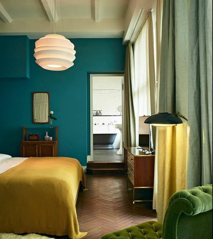 yetişkin yatak odasında ördek mavisi dekor fikri, yeşil koltuk, beyaz tasarım sarkıt lamba, hardal sarısı yatak örtüsü, ahşap parke, eski mobilyalar